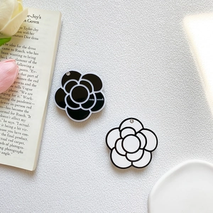 Elegant black and white camellia flower phone grips on a minimalist white leather surface