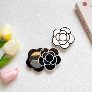 Detail showing white camellia phone grip with mirror on a marble tabletop with tulips