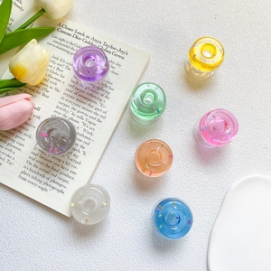 Colorful clear resin donut phone grip stands with glitter flakes on a clean background