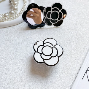 Close-up of camellia shaped phone stand with folding mirror in black and white finish