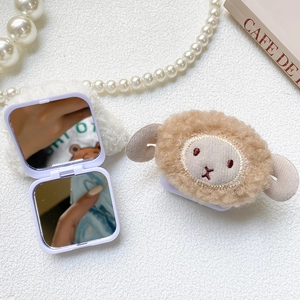 Detail view of purple folding makeup mirror with brown plush lamb on white textured surface