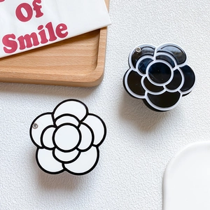 Detailed view of modern camellia flower phone grips in glossy black and white finish