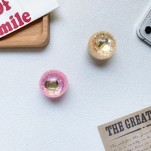 Close-up of heart sequins phone socket grip with golden heart inlay on white texture