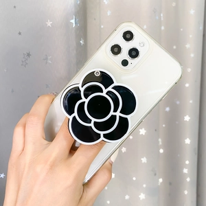 Minimalist black and white camellia flower phone socket holder on white smartphone