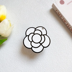 Minimalist black and white camellia flower phone grip on aesthetic desk setup
