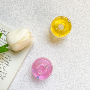Detailed macro view of donut-shaped translucent resin phone grips in yellow and pink
