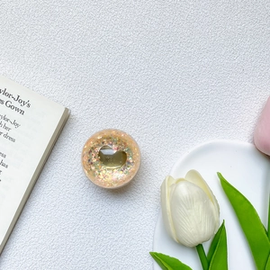 Detail view of round glitter phone grip with gold heart sequins on an aesthetic background