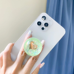 Detail of green glitter phone grip with golden heart on white smartphone case