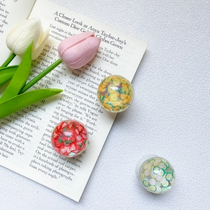 Close-up of three clear resin phone grips featuring strawberry, orange, and lemon slices