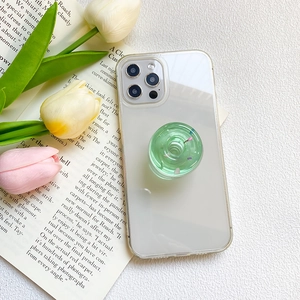Detail showing a green donut-shaped phone grip attached to a clear protective case