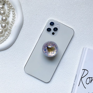 Sparkling transparent phone griptok with gold heart and colorful sequins on smartphone