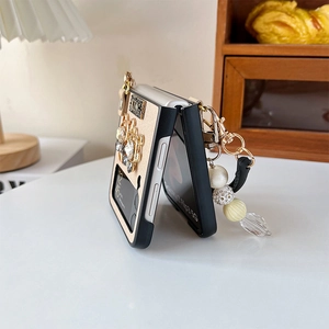 Detail of luxury Galaxy Z Flip case with King plaque, rhinestones and pearl handle strap