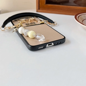 Detail view of Galaxy Z Flip phone case with pearl keychain and gold leather finish