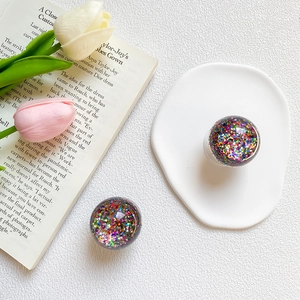 Detailed view of resin phone grips with colorful sparkling sequins and crystal ball design