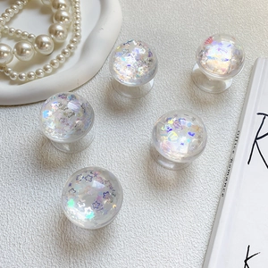 Macro detail of transparent pop socket with holographic star sequins and shell glitters