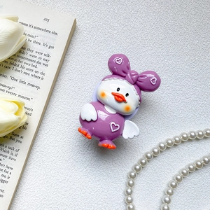 Dettaglio del supporto per telefono a forma di papera viola 3D su un libro