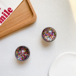 Macro shot of colorful glitter crystal balls with sparkling sequins on a clean white surface