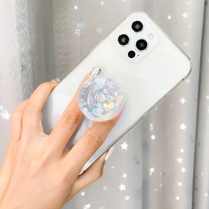Clear heart sequin phone grip with shell elements on a smartphone, hand-held view