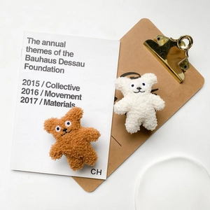 Macro detail of plush teddy bear mobile phone holders in brown and white woolly texture