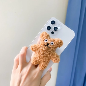 Cute brown plush teddy bear expandable phone grip stand on a white smartphone