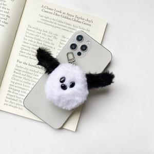 Close-up of cute plush dog phone grip accessory with black ears on white faux fur