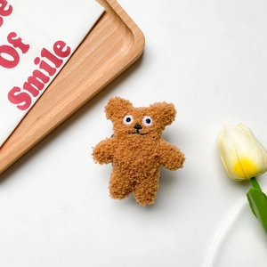 Close-up of cute plush brown bear phone stand with curly fur and embroidery detail