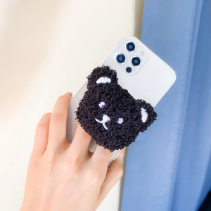 Detail of cute black plush bear phone socket grip attached to a smartphone