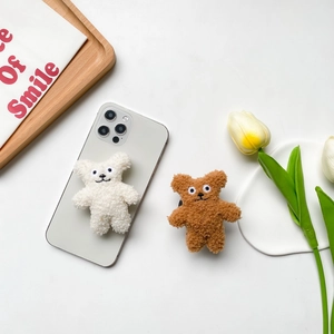 Close-up of cute plush bear phone socket stand in white and brown lamb wool material