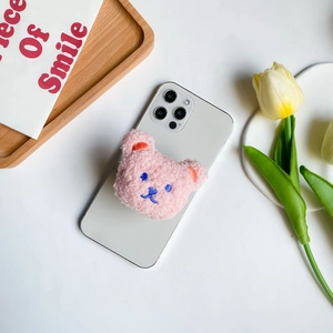 Detail of pink plush bear phone grip on white smartphone with aesthetic tulip decor