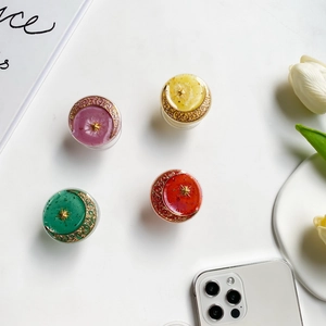 Flat lay of four glitter resin phone grips with moon and star accents in vibrant colors