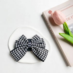 Detail shot of black and white houndstooth bow phone grip on white ceramic plate