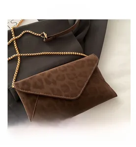 Détail d'une pochette léopard avec bandoulière chaîne dorée et texture en daim doux