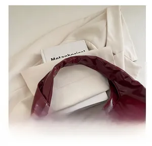 Detail view of burgundy patent leather handbag featuring comfortable top handle and glossy finish