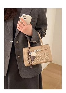 Détail d'un sac matelassé beige avec fermoir argenté et pendentif cœur décoratif