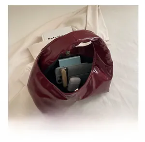 Detail view of burgundy patent leather tote bag interior showing its large storage capacity