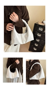 Detail of white half-moon hobo bag with vertical seam design and polished finish