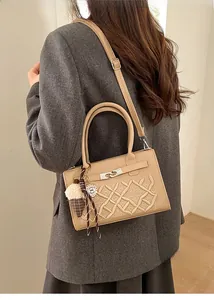 Detail showing embroidered beige handbag with metal clasp and plush pendant charm