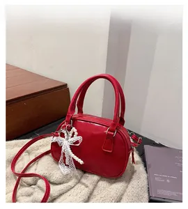 Detail of red bowling bag featuring pearl and lace bow charm with adjustable strap
