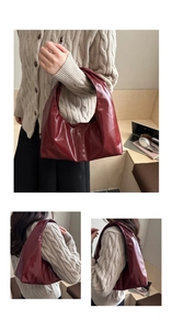 Detail of burgundy glossy leather underarm bag with minimalist strap and stitching