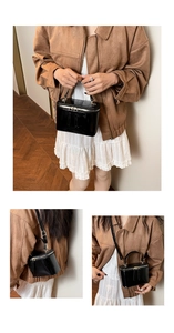 Detailed macro view of black patent leather crossbody bag with golden zipper and tassels