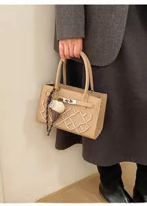 Detail of khaki quilted handbag featuring embroidered crown logo and ice cream plush charm