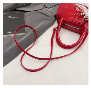Detail of red baguette shoulder bag featuring white pearl and lace bow decorations