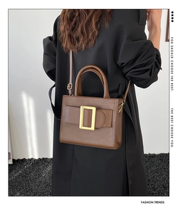 Brown handbag with a signature large gold square buckle shown with a black coat