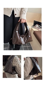 Close-up of a coffee brown glossy crescent underarm bag with sleek stitching detail