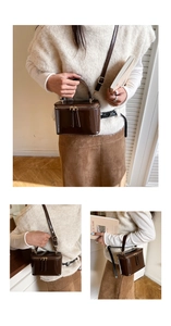 Detail of a brown patent leather box handbag with gold double zippers and top handle