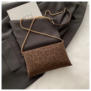 Pochette léopard avec bandoulière chaîne dorée sur un blazer gris chic