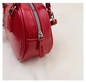 Detailed view of the smooth silver zipper and red leather puller on a stylish handbag