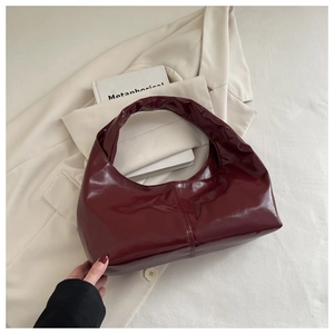 Detail of burgundy patent leather hobo bag with smooth stitching and high gloss finish