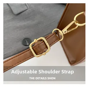 Detail of adjustable brown leather shoulder strap with polished gold-tone metal buckle