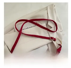 Détail du sac bandoulière en daim rouge avec anneaux dorés et rivets métalliques